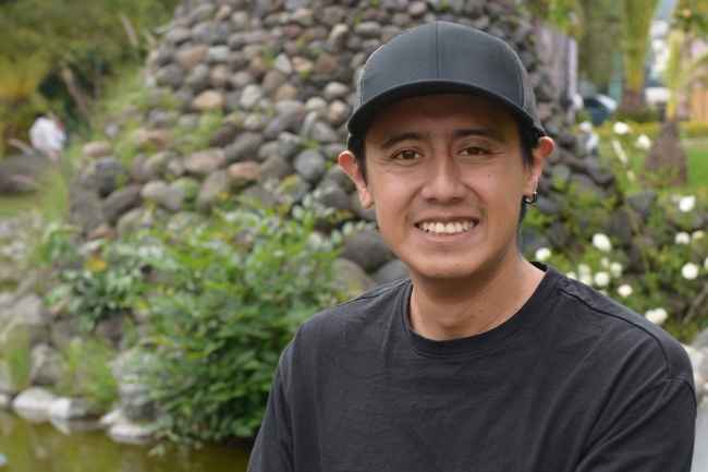 Participant Jimmy - person with short dark hair wearing a black baseball hat and smiling outside