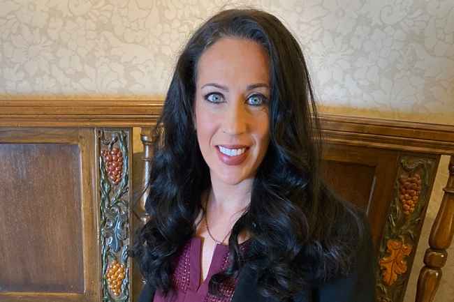 Participant Cali - person with long dark hair wearing black and smiling