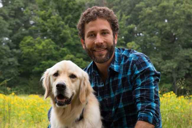 Participant Jeff - person with short curly brown hair smiling with a golden retriever outside