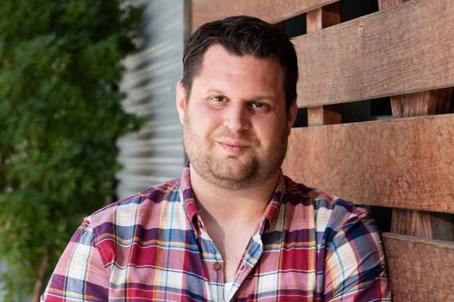 Participant Joe - person with short dark hair wearing a red plaid shirt outside