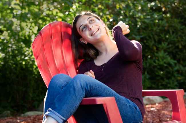 Deconstructing Stigma participant Jessica - person sits and laughs on red outdoor chair