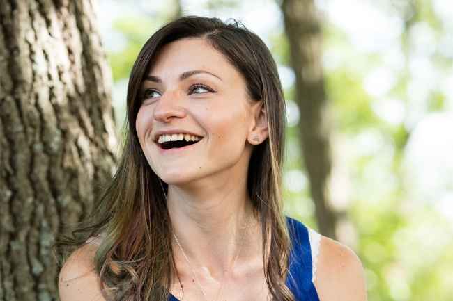 Deconstructing Stigma participant Jessika - Person in blue tank top sits by tree