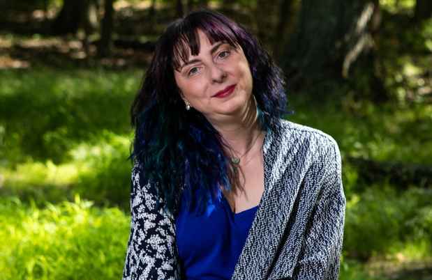 Participant Kim - person with dark hair dyed blue at the ends sitting outside