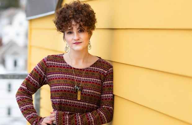 Participant Julia - person in red sweater standing in front of yellow building