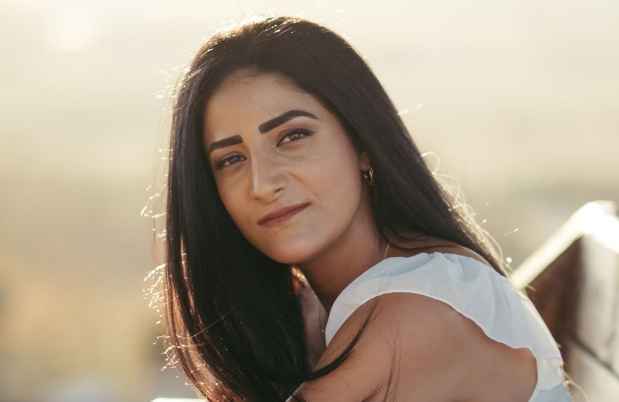 Deconstructing Stigma participant Rotem - person with long dark hair and white shirt standing in field 