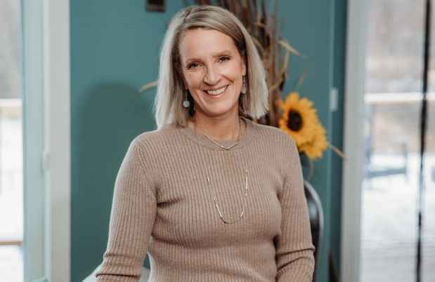 Participant Kelli - person in brown sweater in front of teal wall