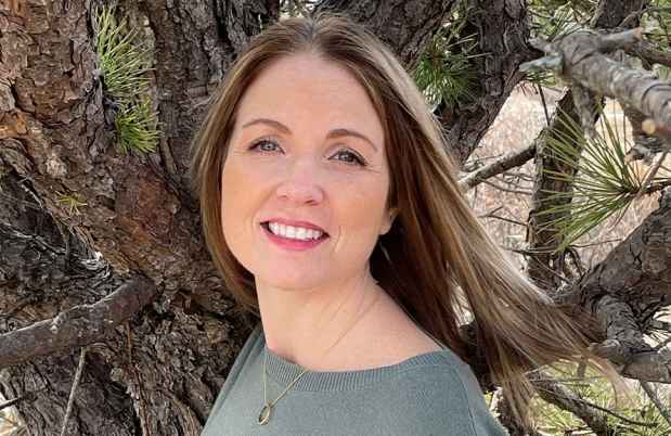 Participant Lindsay - person in sweater smiling in front of a tree