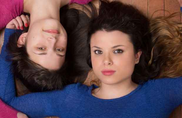 Participant Abby is lying on the floor holding hands with her sister Mary