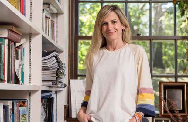 Participant Kim - person in white shirt with colorful sleeves in a room with books and a window with greenery
