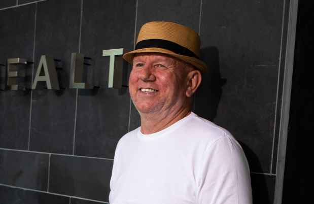 Participant Michael - person in white shirt wearing a hat in front of a dark tiled wall