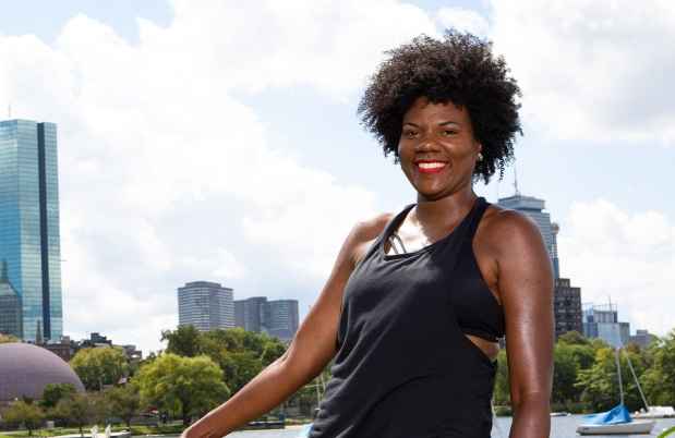 Participant Nieisha - person with dark curly hair smiling in front of the Boston skyline