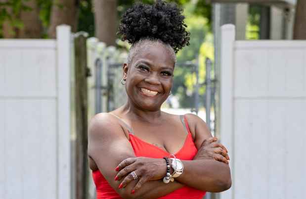 Participant Norma - person with dark curly hair wearing a red dress smiling outside