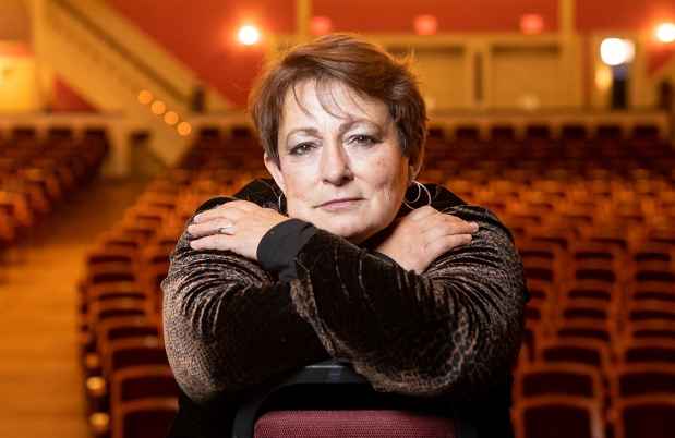 Participant Nancy - person with short brown hair leaning on a chair in a theater