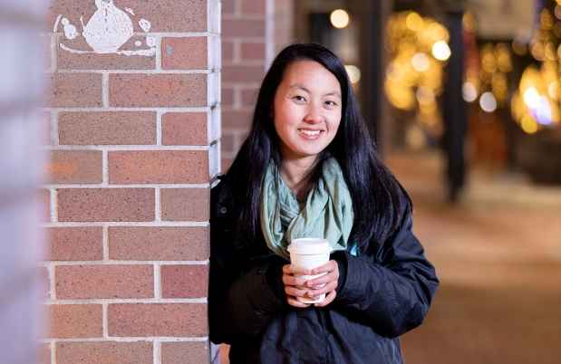 Participant Tian - person with long dark hair outside, there are trees with lights in the background