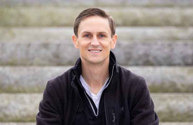 Participant Justin - person in black sweatshirt sitting on stone steps