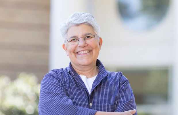 Participant Olga - person with short white hair wearing a blue shirt and smiling outside