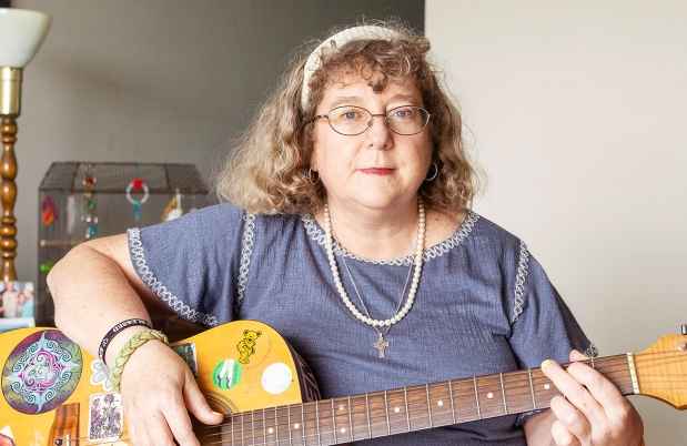 Participant Mary - person with wavy grey hair holding a guitar