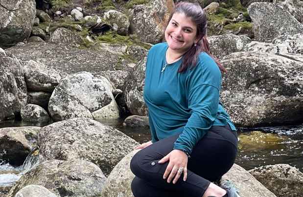 Participant Amanda sitting on a large rock in a stream