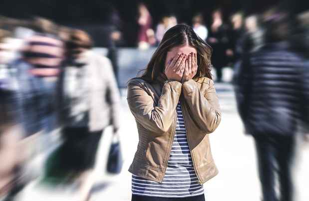 Person stands in crowd with hands over eyes