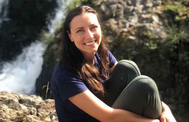 Participant Natalia - person with long brown hair sitting on a large rock outside