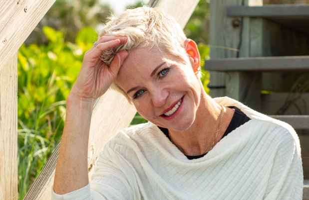 Participant Molly - person with short blond hair smiling on an outdoor wooden staircase