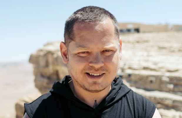 Deconstructing Stigma participant Lavih - Person stands outside in desert with boulder behind