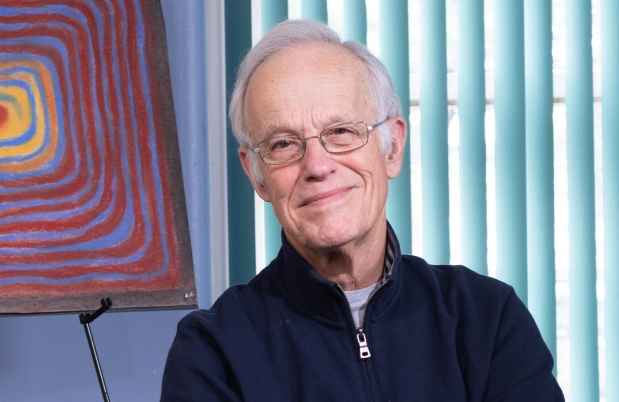 Participant Robert - person with short white hair and glasses smiling with a piece of art