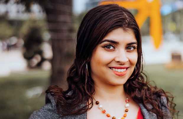 Participant Mrinal - person with wavy brown hair smiling outside