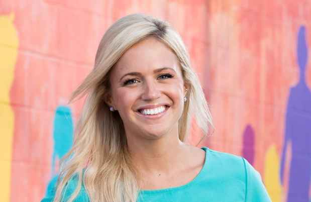 Participant Meg - person with long blond hair smiling in front of a colorful painted wall