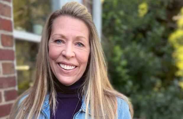 Participant Renee - person with long blond hair in a jean jacked smiling in front of greenery