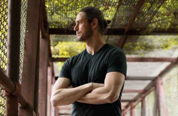 Deconstructing Stigma participant Sean - person stands in chainlink fence bridge