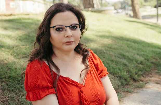 Deconstructing Stigma participant Shlomit-Coana - person in red dress and glasses sits outside