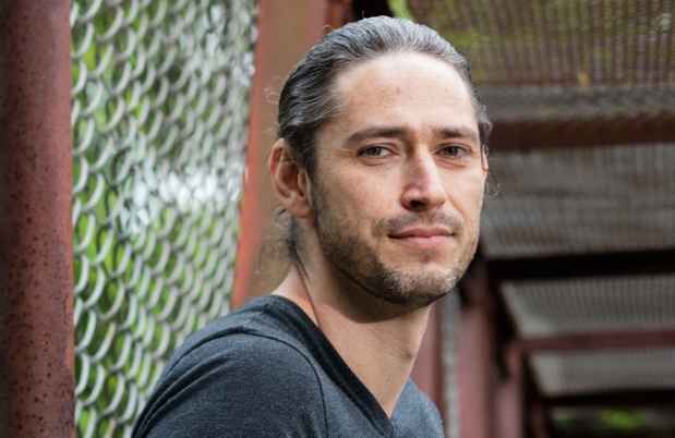Deconstructing Stigma participant Sean - person leans against chain link fence
