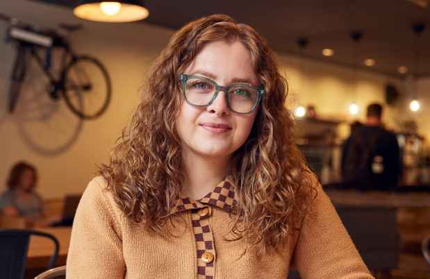 Participant Courtney - person with long wavy hair and glasses smiling