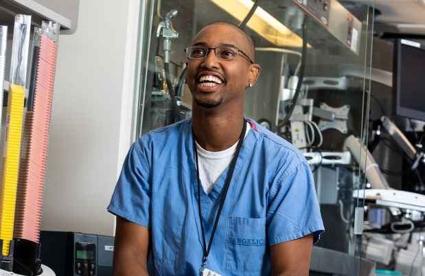 Participant Charles - person with very short hair and glasses wearing blue scrubs and laughing