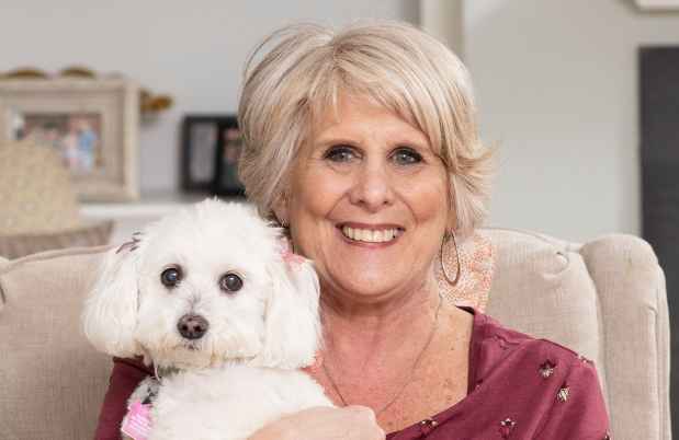Participant Jane - person with short white hair smiling with a small white dog