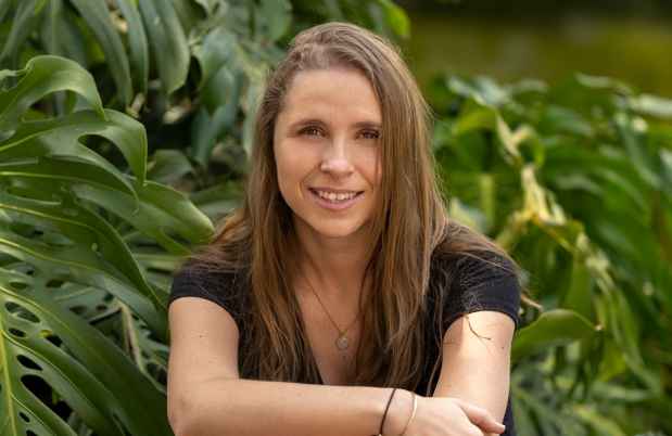 Deconstructing Stigma participant Andrea - person sits by river with big tropical leaves in background