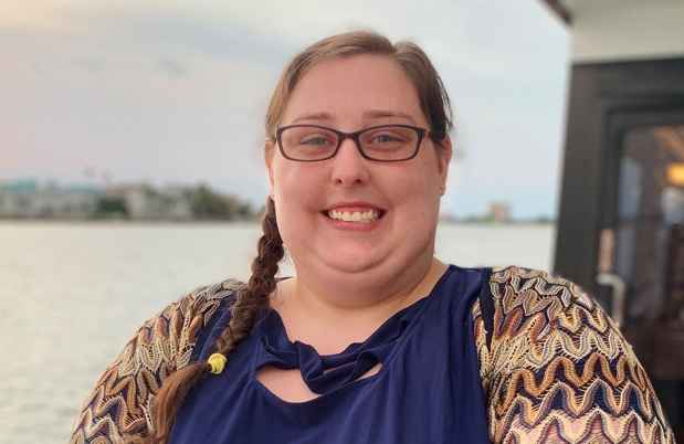 Participant Elizabeth - person with long dark hair and glasses smiling outside