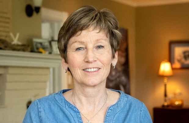 Participant Ann - person with short blond hair smiling in a room with a lamp
