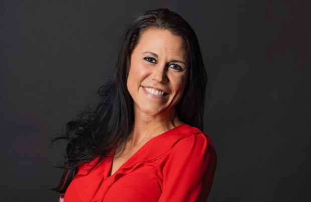Participant Jen - person with long dark hair wearing a red shirt and smiling in front of a dark background