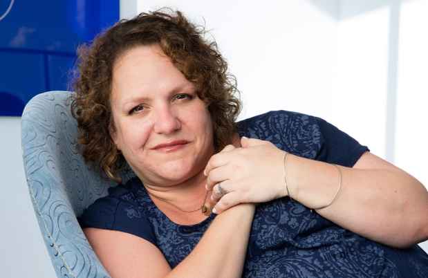 Participant Jamie - person with curly auburn hair smiling in a blue chair