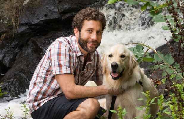 Participant Jeff - person with short curly brown hair smiling with a golden retriever outside