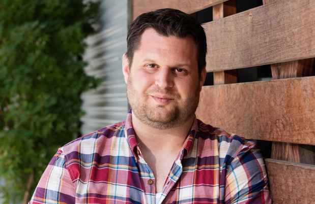 Participant Joe - person with short dark hair wearing a red plaid shirt outside