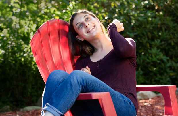 Deconstructing Stigma participant Jessica - person sits and laughs on red outdoor chair