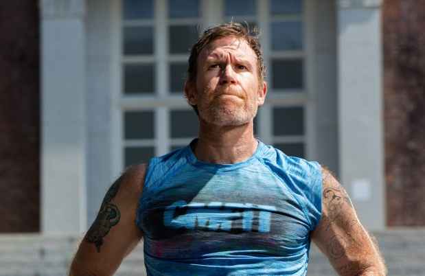 Participant Alan - person with short brown hair wearing a blue tank top standing in front of stone steps outside