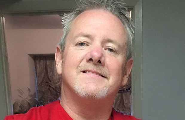 Participant Robb wearing a red doctors scrub smiling