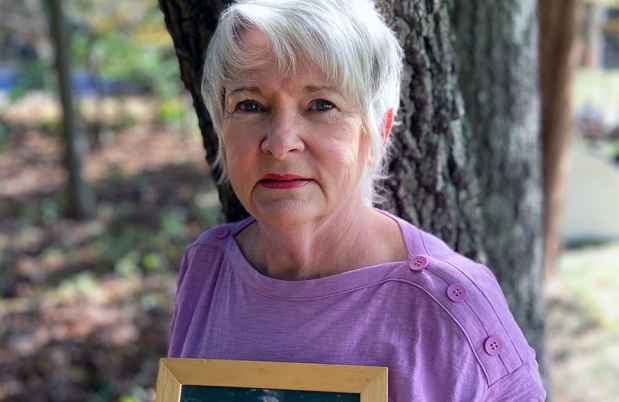 Participant Suzanne standing outside holding a framed photo