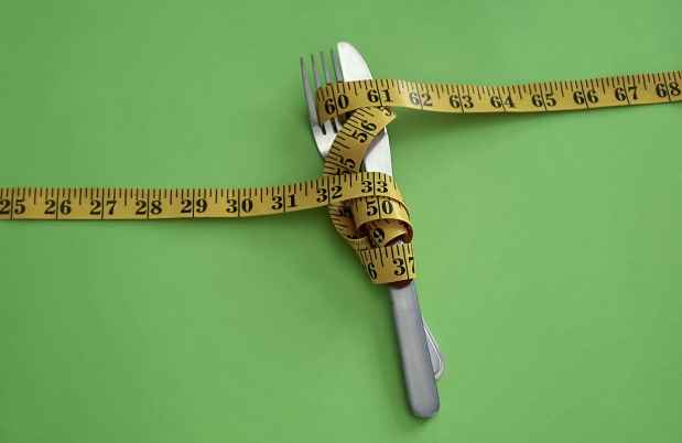 Measuring tape, knife, and fork on green background