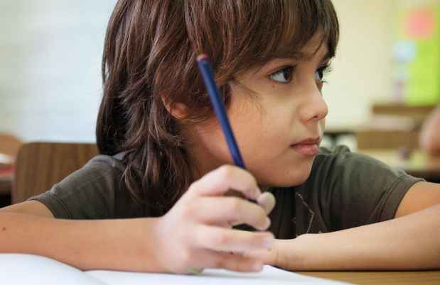 Child holds pencil in classroom