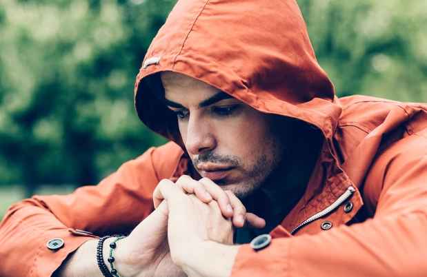 Person in orange hoodie sits outside